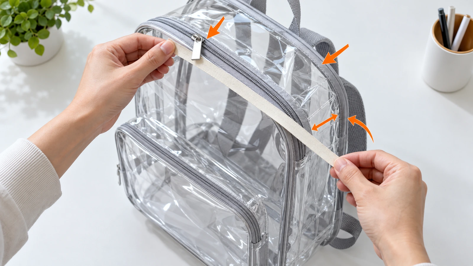 يدان تقيسان الارتفاع الخارجي والعرض وعمق الضلع الجانبي لحقيبة ظهر PVC شفافة بشريط قياس عادي، مع أسهم تبيّن أن مقابض السحّاب وشريط الحافة تُحتسب ضمن الحجم